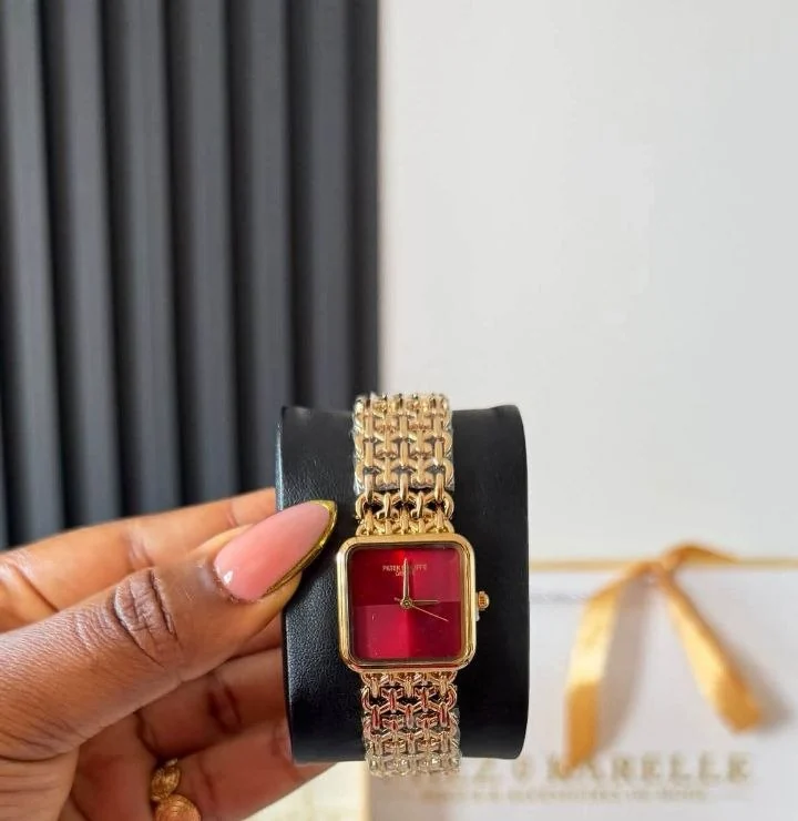 Montre bijou maille dorée à cadran carré rouge, présentée à la main